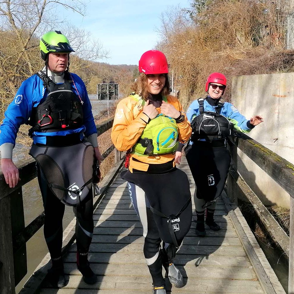 Paddeltour auf der Lahn Drei Paddler laufen über einem Holzsteg.